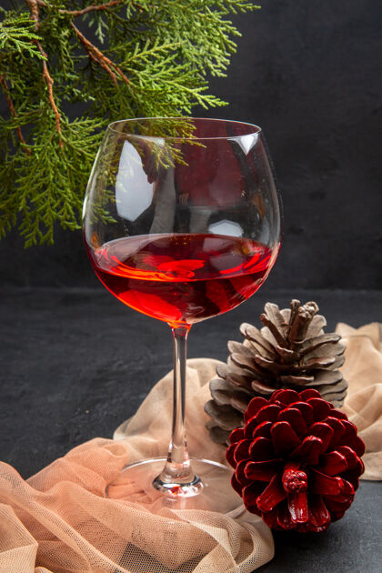 庆典垂直视图美味的红酒在一个玻璃高脚杯毛巾和冷杉枝针叶树锥在黑暗的背景玻璃高脚杯酒精
