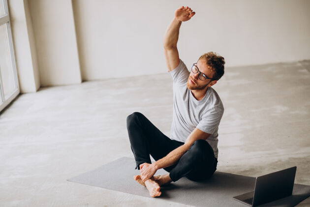冥想运动的男人看教程和练习瑜伽垫上瑜伽姿势健身工作室