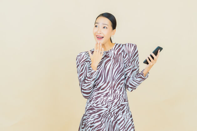女人肖像美丽的亚洲年轻女子微笑着智能手机米色屏幕电话消息