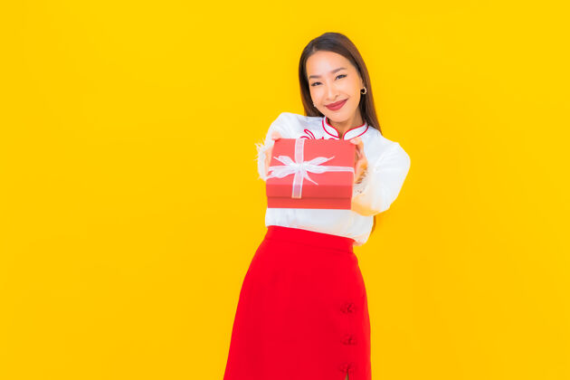 新肖像美丽的亚洲年轻女子与红色礼盒黄色美女庆祝高兴