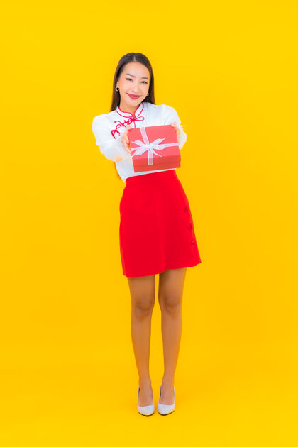 中国肖像美丽的亚洲年轻女子与红色礼盒黄色礼物给予泰国