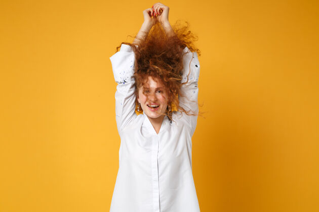 时尚快乐的年轻红发女 穿着白衬衫 孤零零地站在橘黄色的墙上女性风一个
