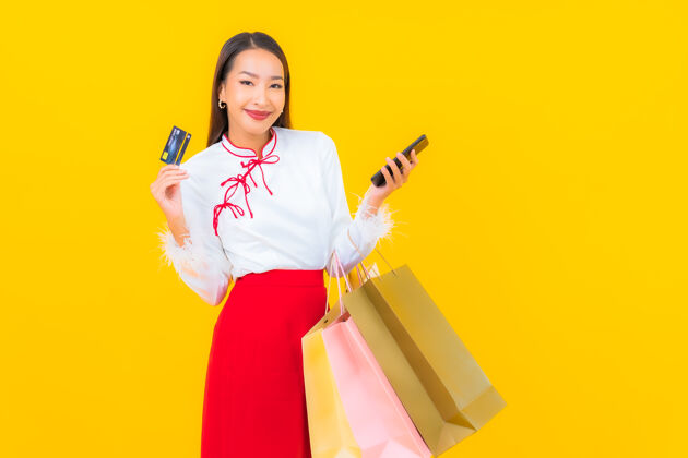 销售一位年轻漂亮的亚洲女士 手拿购物袋 信用卡 黄色包交易女性