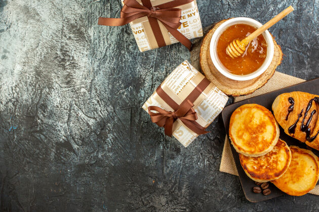 盒俯瞰美味的早餐与薄煎饼木制砧板蜂蜜美丽的礼品盒在黑暗的表面香料容器视图
