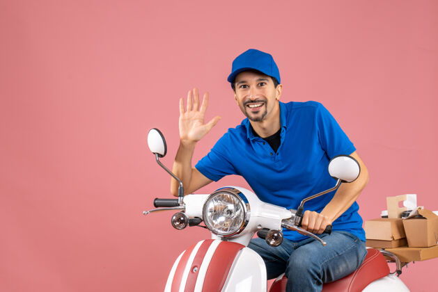 前面前视图微笑的信使家伙戴着帽子坐在滑板车上显示五个粉彩桃背景摩托车背景人物