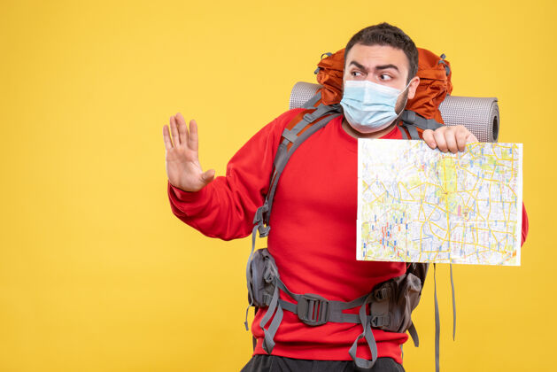 表演上图是一个迷茫的旅行者 他戴着医用面罩 背包里放着黄色背景上的5张地图男性人物背景