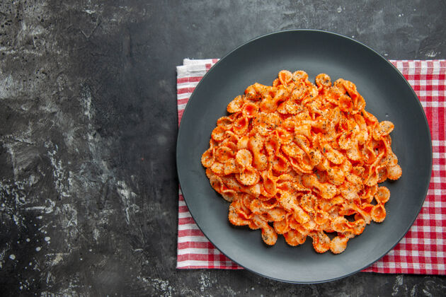 晚餐上图：在一个黑色的盘子上 用一块红色的条布做晚餐 可以看到简单的意大利面炒锅蔬菜毛巾