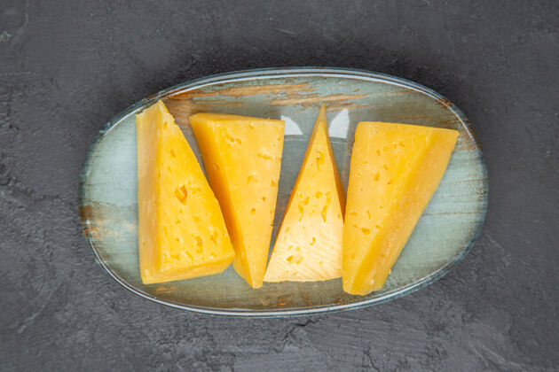奶酪在黑色背景的蓝色盘子上俯瞰美味的黄色切片奶酪新鲜健康一餐
