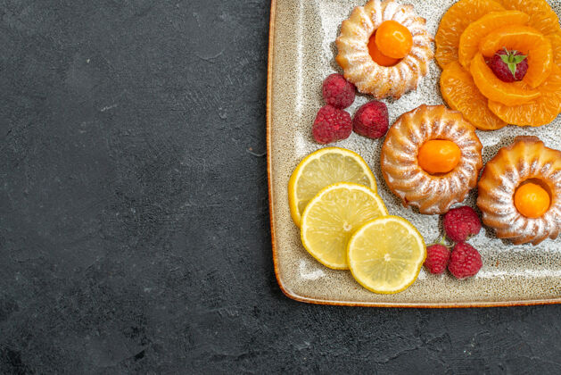 切片俯瞰美味的小蛋糕柠檬片和橘子上的深色背景水果饼干甜茶饼干饮食柑橘饼干