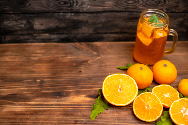 背景全切新鲜橙子的俯视图 左边是一个棕色背景的玻璃杯 里面有叶子和天然果汁果汁叶子柠檬