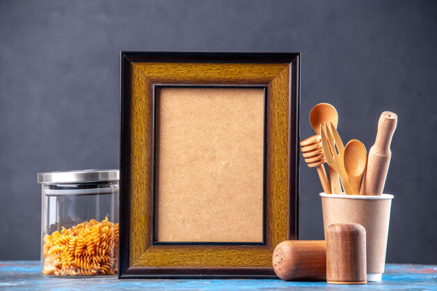 玻璃正面图内空相框不同的香料意大利面在一个玻璃壶木制勺子上蓝色的桌子视图里面古董