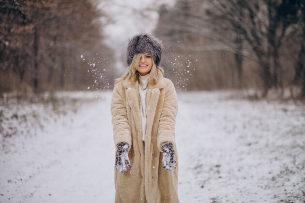 帽子美丽的女人在满是雪的公园里散步雪休闲心情