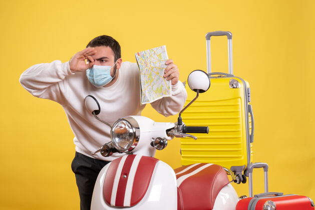 人旅行概念的俯视图 戴着医用面罩的人站在摩托车旁边 黄色手提箱在上面 手里拿着车票面具训练健身