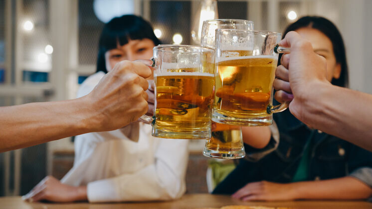 酒吧一群快乐的亚洲年轻游客朋友在考山路的夜总会喝酒或喝手工啤酒 开派对亚洲社交夜生活
