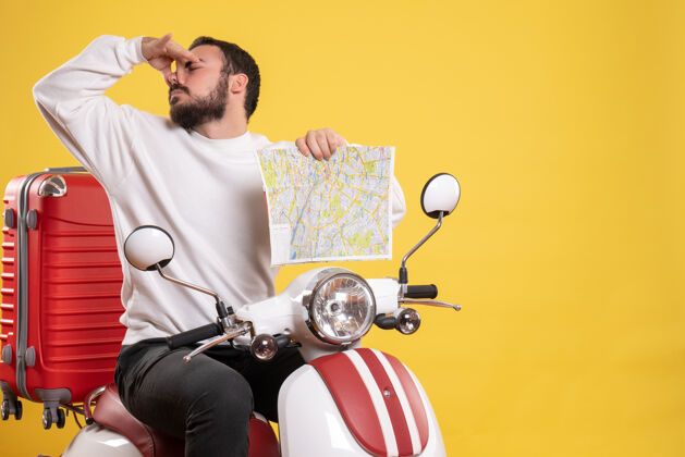气味旅行的概念与年轻人坐在摩托车上的手提箱作出不良气味的手势上黄色手提箱摩托车手势