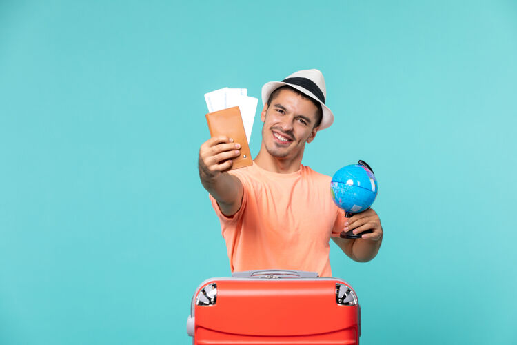 肖像度假的男人拿着小地球仪和浅蓝色的机票地球举行度假区
