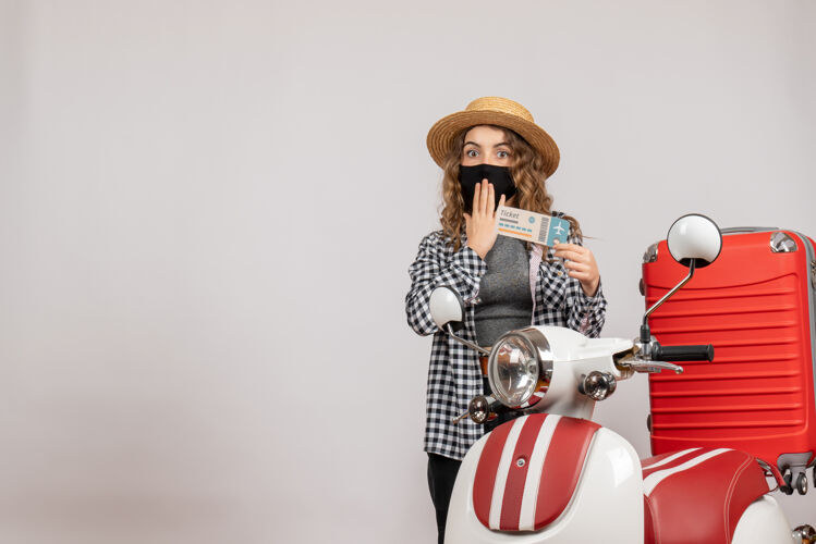 服装一个拿着票的漂亮女人站在轻便摩托车的红色手提箱旁边衣服票时尚