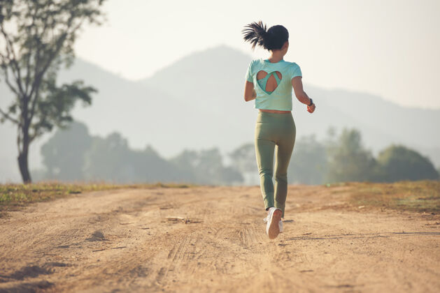 运动年轻女士享受着健康的生活方式 一边在乡村公路上慢跑 一边在户外锻炼和健身年轻女士在日落时分在乡村公路上跑步健活方式女性速度