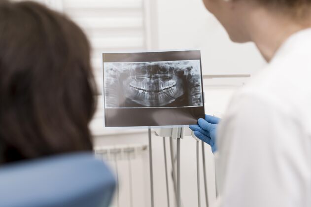 雇员女病人和牙医一起看牙齿的X光片女性水平从业者