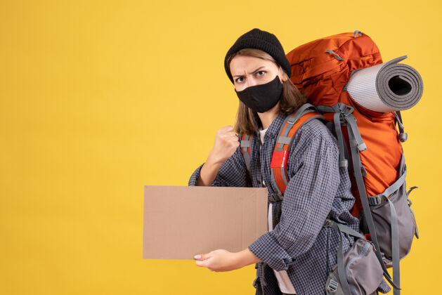 背包强壮的女旅行者 戴着黑色面具 背着硬纸板的背包面具黑成年人