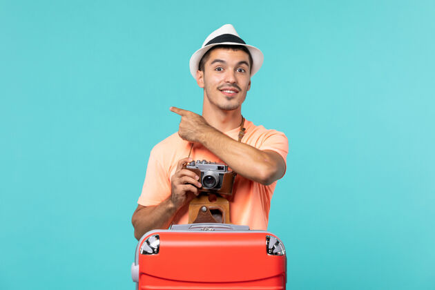 照片带着他的大红色手提箱和相机在蓝色的天空上拍照的度假男人假期旅行相机