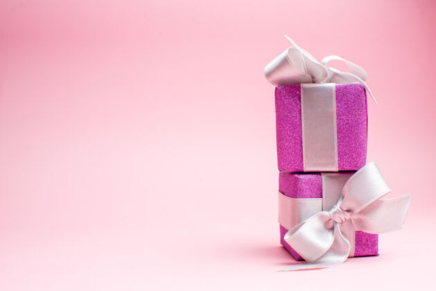 庆祝正面视图小圣诞礼物上粉红色圣诞彩色礼品照片新年假期免费空间圣诞节包装购物
