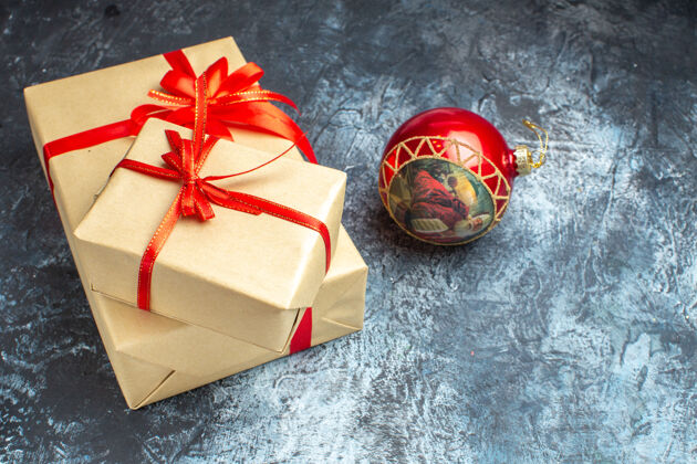庆祝前视图圣诞礼物与红色蝴蝶结绑在浅色深色新年假期圣诞礼物照片圣诞节前面弓