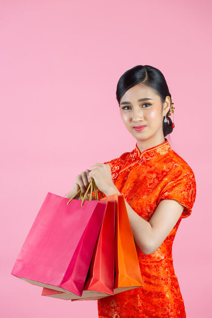 女性美丽的亚洲女人快乐的微笑和购物在中国新年的粉红色背景年人欢呼