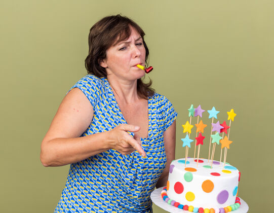 年龄中年妇女拿着生日蛋糕吹口哨 用食指指着站在绿色墙壁上的某个看起来很内向的庆祝生日聚会手指口哨目录