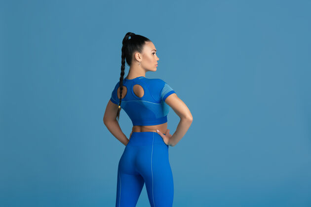 锻炼性感的姿势美丽的年轻女运动员在工作室练习 单色蓝色肖像健康强壮动作