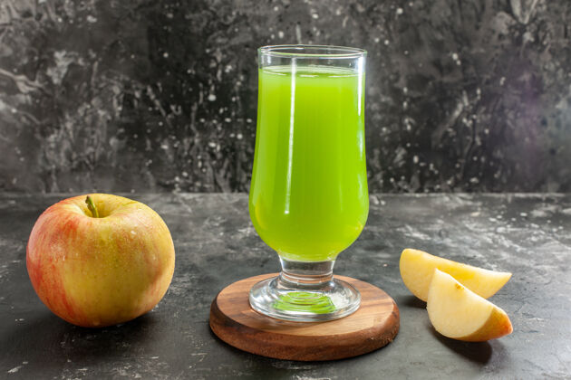水果前视图新鲜成熟的苹果与绿色的苹果汁在黑暗的桌子上醇厚的果汁树照片的颜色柑橘果汁玻璃杯