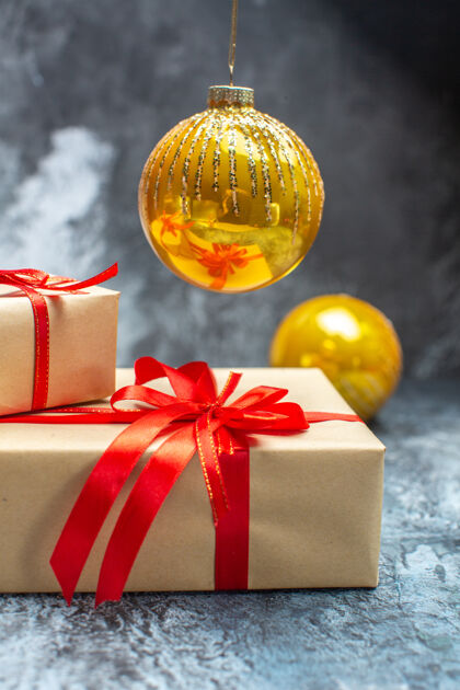 庆祝前视图圣诞礼物与红色蝴蝶结和玩具绑在浅色深色照片新年假期彩色圣诞礼物圣诞节玩具前面