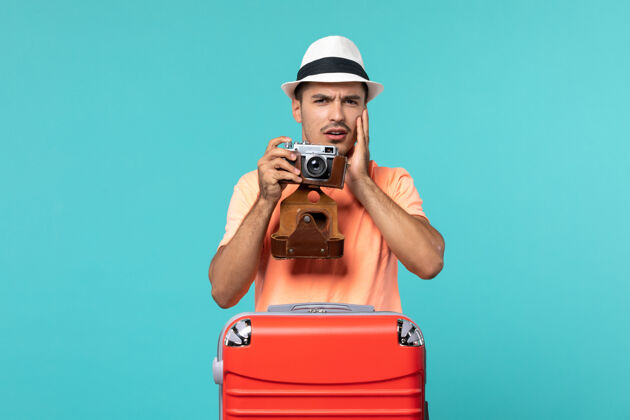包带着红色手提箱和蓝色相机拍照的度假男人相机人假期