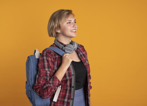 太空微笑着的年轻斯拉夫女学生戴着耳机 背着背包站在一边女孩站着穿