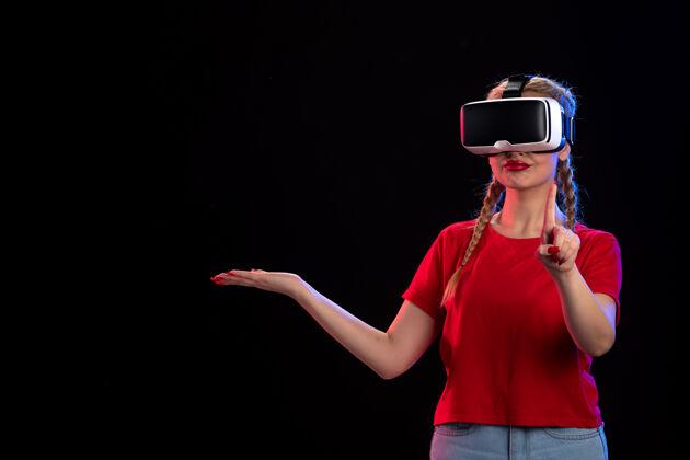 成人年轻女性在黑暗的墙上玩vr的正面图视图虚拟现实游戏