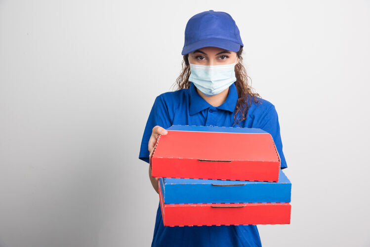 帽子送比萨饼的女孩手里拿着三盒白色的医用面膜成人女士面罩