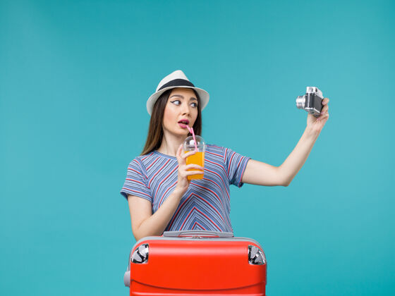 微笑前景：度假中的女人拿着果汁和相机在蓝色的背景下航行 暑假旅行 海上旅行成人相机果汁