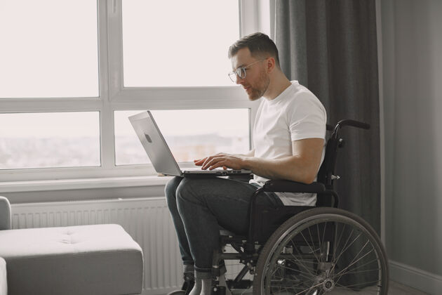 笔记本电脑残疾人使用笔记本电脑开朗帅哥呆在家里远程工作房子情绪医疗