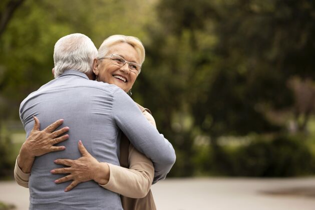 老年中景男女在户外拥抱爱情故事退休老年