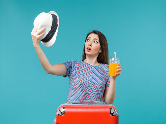 微笑前景度假妇女手持果汁和帽子在蓝色背景上航行旅行度假海上旅行美丽举行肖像
