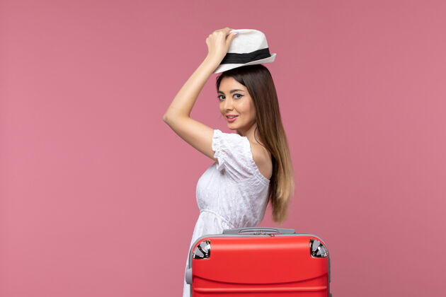 成人正面图浅粉色背景上的年轻女性正在为度假做准备出国旅游出海肖像准备年轻女性