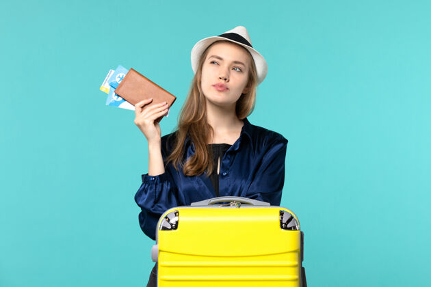 年轻女子正面图年轻女子拿着她的机票 准备乘坐蓝色背景的旅行飞机出海度假旅行肖像举行准备
