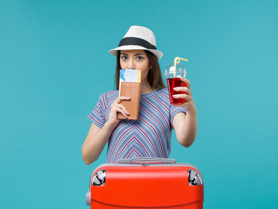 脸前景度假中的女人拿着果汁拿着蓝色书桌上的机票旅行女海飞机夏天女肖像果汁