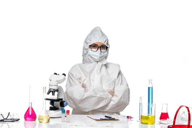 医生正面图年轻的女化学家穿着特殊的防护服 正坐在白色背景的病毒实验室里 化学健康防护特殊实验室