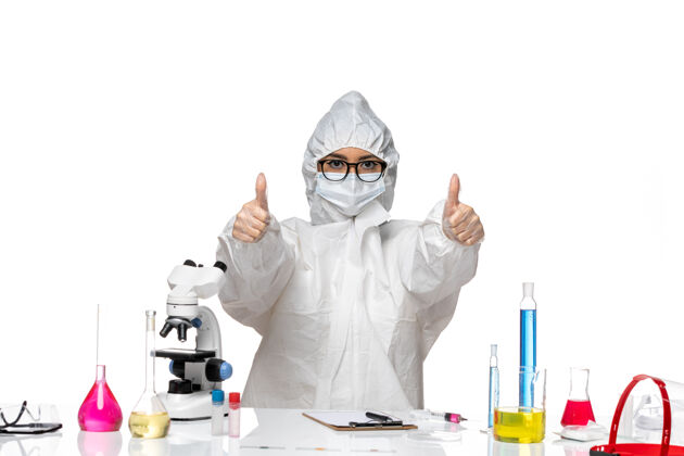 坐姿前视图穿着特殊防护服的年轻女化学家正坐在一个白色背景病毒实验室的化学健康化学面罩防护