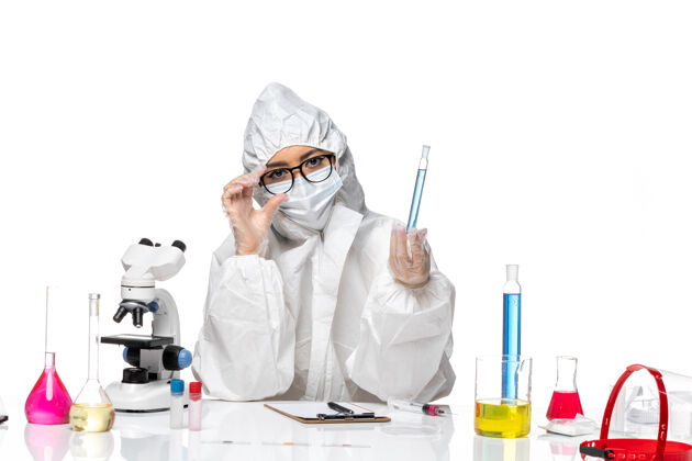 专业正面图身穿特殊防护服的年轻女化学家拿着白色背景上蓝色溶液的烧瓶 科维化学病毒实验室病毒实验室外套保温瓶