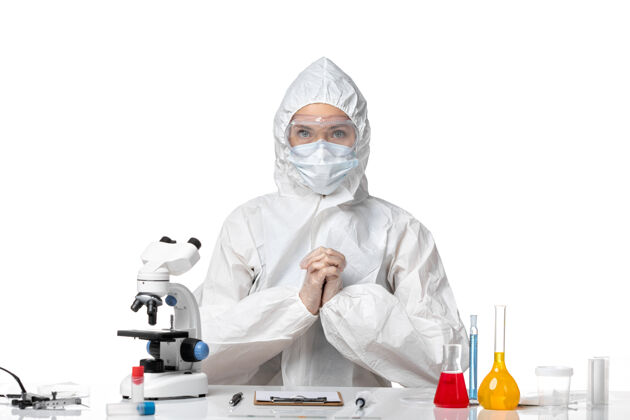 病毒正面图年轻女医生穿着防护服 戴着口罩 因为在浅白色背景上有冠状病毒专业套装诊所