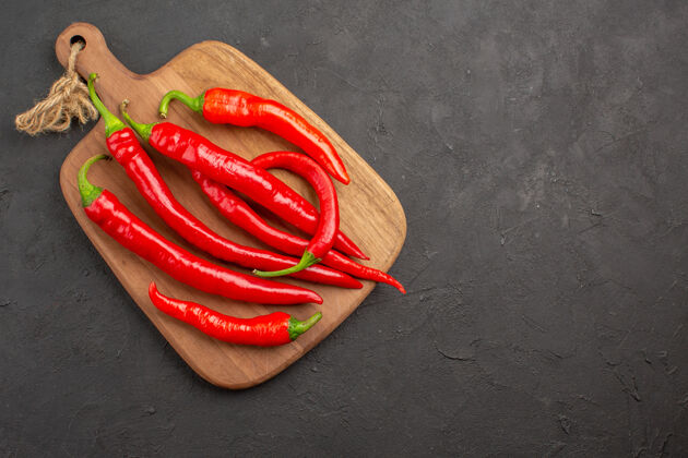 辣椒顶视图红色辣椒在一个对角线砧板在左边的黑色桌子与复制空间弹性装置烹饪颜色