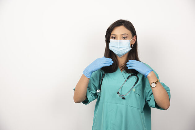 工作戴口罩的女医生在白色背景上检查头发高质量照片听诊器医疗女性