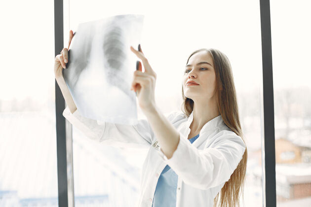 年轻人窗户上的X光片长头发的女人穿着工作服的医生成人专家窗户